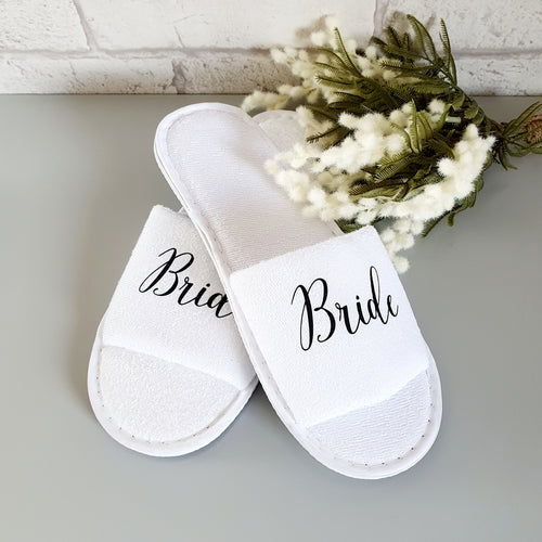 white, towelling, open toed slippers with the word bride across the front. 