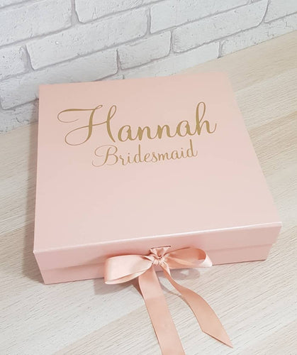 square rose gold gift box with a name and role in gold text on the front. 
